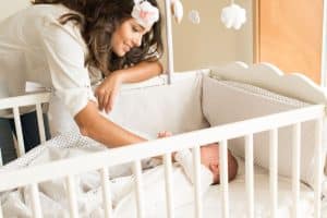maman mettant le bébé dans le lit évolutif pour dormir